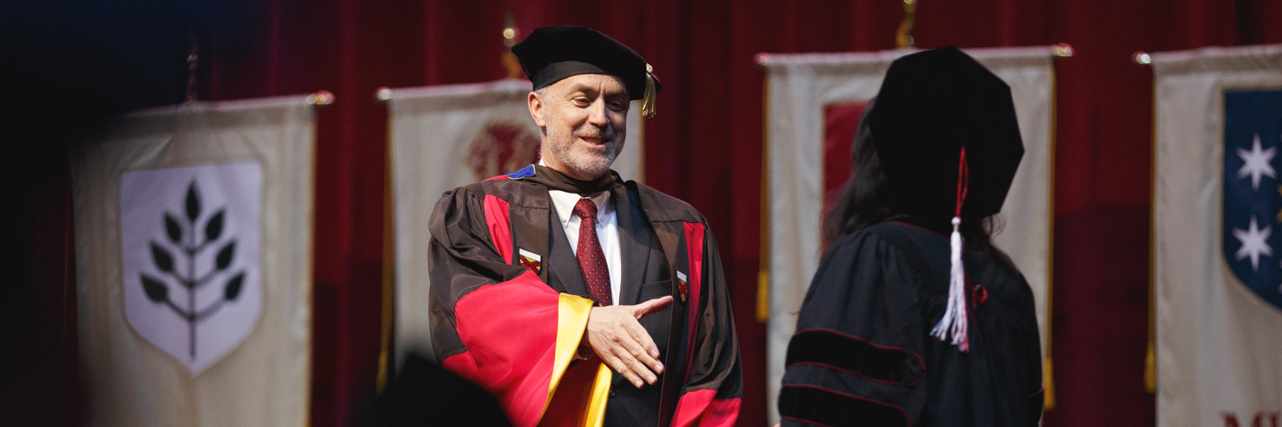 Graduate School Dean David Daleke shaking a student's hand at Commencement.