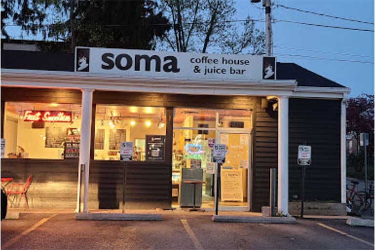 An image of the SOMA coffee house & juice bar on an early morning, all aglow from the lights inside.