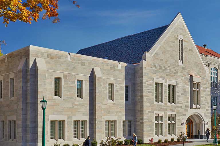 An image of Swain Hall highlighting it's beautiful limestone façade with some students walking in the foreground.