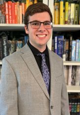 Photo of Austin Medlin standing in front of a bookcase